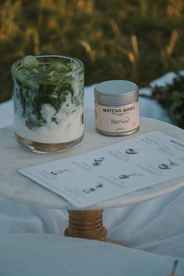 Tin with layered matcha drink on a table